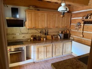 a kitchen with wooden cabinets and a counter top at Goralska Chalupa in Vígľaš