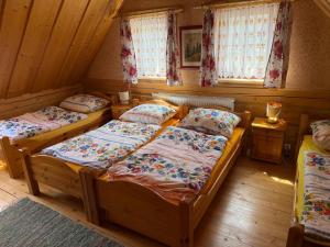 a bedroom with two beds and two windows at Goralska Chalupa in Vígľaš