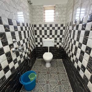a bathroom with a toilet and black and white tiles at The Human Nest Coliving in Bhubaneshwar +43 photos