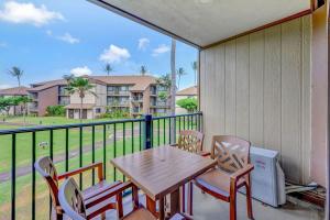 a table and chairs on a balcony with a view of a building at Kauai Serenity Condo Pono Kai Resort E206 in Kapaa