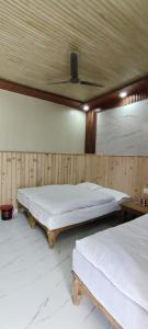 two beds in a room with a ceiling at Hotel Him darshan in Madheso
