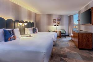 a hotel room with two beds and a flat screen tv at The Royal Sonesta Boston in Cambridge