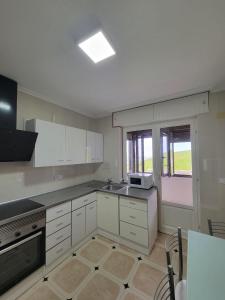 a kitchen with white cabinets and a sink and a window at CASA FREDO in Cóbreces