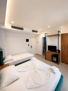 two beds in a large room with a tv at Prestige Hotel in Ksamil
