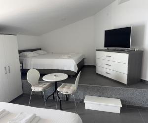 a bedroom with a bed and a tv and a table and chairs at Apartments Lukrecia in Neum
