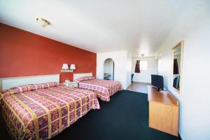 a hotel room with two beds and a flat screen tv at Superior Suites Phoenix Mesa in Mesa