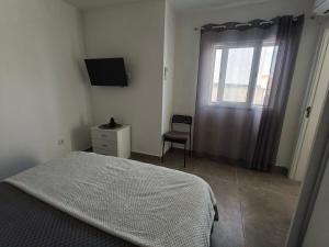 a bedroom with a bed and a window and a chair at O Refúgio in Mértola