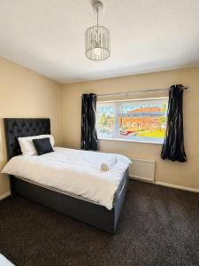a bedroom with a large bed and a window at Nayla House Cozy 4BR with Garden & Parking in Moffat