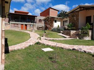 a house with a stone walkway in the yard at Hotel Norte Potosí in Torotoro