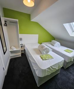 two beds in a room with a green wall at The Roost in Derry Londonderry