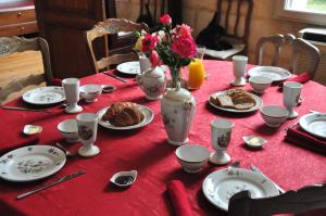 a red table with plates of food and flowers on it at Chateauneuf in Sadirac