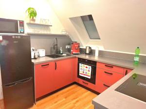 a kitchen with red cabinets and a black refrigerator at Helle Dachgeschosswohnung, neu renoviert & ruhig in Wolfenbüttel