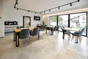 a dining room with tables and chairs and large windows at White House Residence Zator-blisko Energylandii in Zator