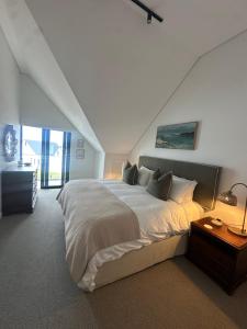 a white bedroom with a large bed and a staircase at St Francis Links- Gallery Deck Links Villas in St Francis Bay