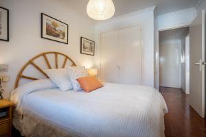 a bedroom with a white bed with an orange pillow at AT070 Piscina, 4 habitaciones, a 180m de la playa in Torredembarra