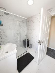 a white bathroom with a shower and a sink at Nayla House Cozy 4BR with Garden & Parking in Moffat +14 photos