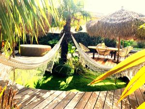 a hammock in a resort with a table and chairs at Maison ambiance cabane exotique climatisée piscine & spa 3 chambres 6 personnes in Messanges +8 photos