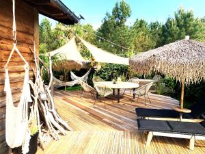 a wooden deck with a table and chairs and a tent at Maison ambiance cabane exotique climatisée piscine & spa 3 chambres 6 personnes in Messanges