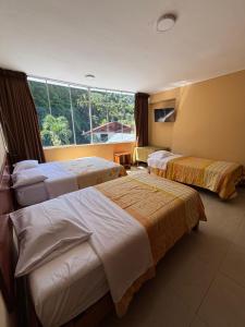 a hotel room with three beds and a window at Cerro Verde in San Ramón