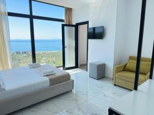 a bedroom with a bed and a chair and a window at Wait 'n Sea in Himare
