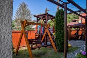 a wooden swing set in a backyard with a gazebo at Villa Cynamon Jacuzzi & Sauna in Wisła