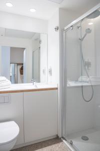 a white bathroom with a shower and a toilet at BABEL COMMUNITY Hôtel Bordeaux in Bordeaux +32 photos