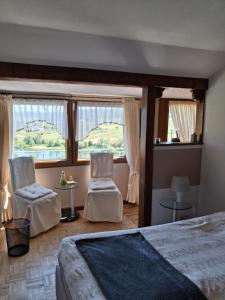 ein Schlafzimmer mit einem Bett, zwei Stühlen und Fenstern in der Unterkunft Hotel Restaurant Würzig in Ürzig in Ürzig