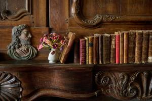 a shelf with books and a bust and a vase of flowers at Castel de Grafeuille in Hautefage