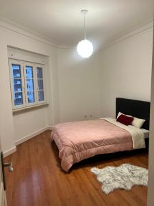 a bedroom with a bed with a pink blanket and a window at The room in Odivelas