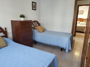 a bedroom with two beds and a dresser and a mirror at Piso Calatrava in Chipiona