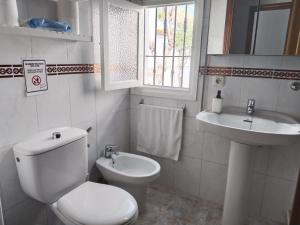 a white bathroom with a toilet and a sink at Piso Calatrava in Chipiona +7 photos