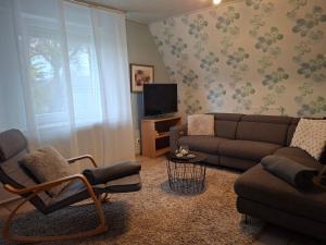 a living room with a couch and a chair and a tv at Ferienwohnung Beatrix in Metelen