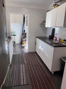 a small kitchen with white cabinets and a brown rug at The room in Odivelas