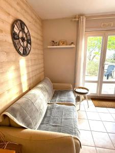 a couch in a room with a clock on the wall at Studio cosy les Sables d'Or in La Guérinière