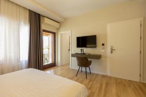 a bedroom with a bed and a desk and a television at Hotel Vila e Arte City Center in Tirana