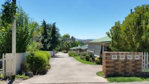 a driveway leading to a house with a fence at Butterfly Cottage in Tumut