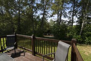 two chairs on a wooden deck with trees at Chalet Le RV 3 in Notre-Dame-Des-Bois