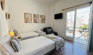 a bedroom with two beds and a balcony at Elina's Rooms in Poros