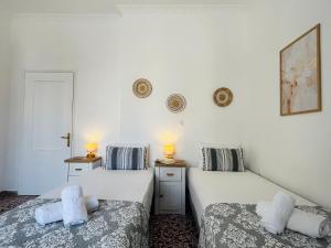 two beds in a room with white walls at Elina's Rooms in Poros