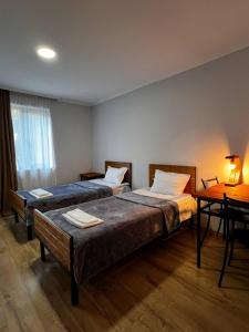 a room with two beds and a table with a desk at Hotel Complex Nabadi in Omalo