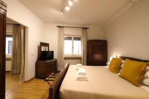 a bedroom with a bed with yellow pillows and a television at Wine Apartments Florence Malvasia in Florence