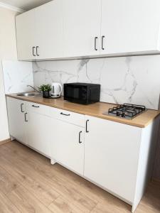 a kitchen with white cabinets and a black microwave at Vienibas apartment in Daugavpils +11 photos