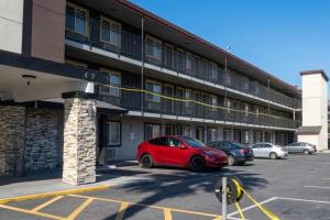 a red car parked in a parking lot in front of a building at Sacramento Inn & Suites Cal Expo I-80 in Sacramento