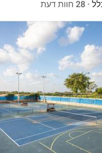 a tennis court with a pool in the background at Rona Suite in Caesarea