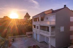 a house with the sun setting in the background at Milina Residence - Lumbarda in Lumbarda