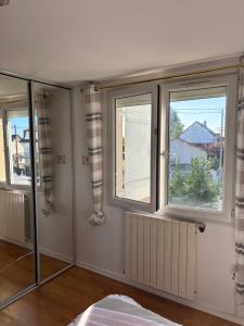 a bedroom with two windows and a radiator at Villa Champigny in Champigny-sur-Marne
