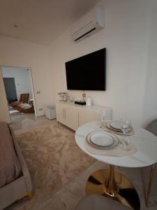 a living room with a white table and a flat screen tv at Suite Crystal Home with Jacuzzi in Trapani