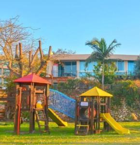 two playground equipment in the grass in front of a building at Rona Suite in Caesarea