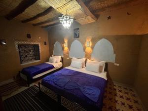 a bedroom with two beds and a chandelier at Riad dar merzouga in Merzouga