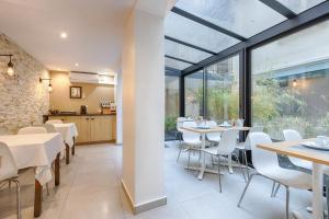 a dining room with tables and chairs and windows at Marmotel Etoile in Paris